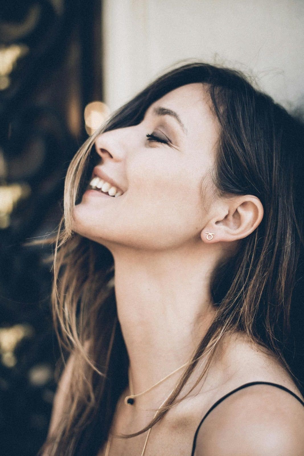 A woman laughs freely with her eyes closed. Healing from trauma in relationships can restore your sense of self and open the door to genuine happiness. A relational trauma therapist in Palm Beach, FL, can help you get there.