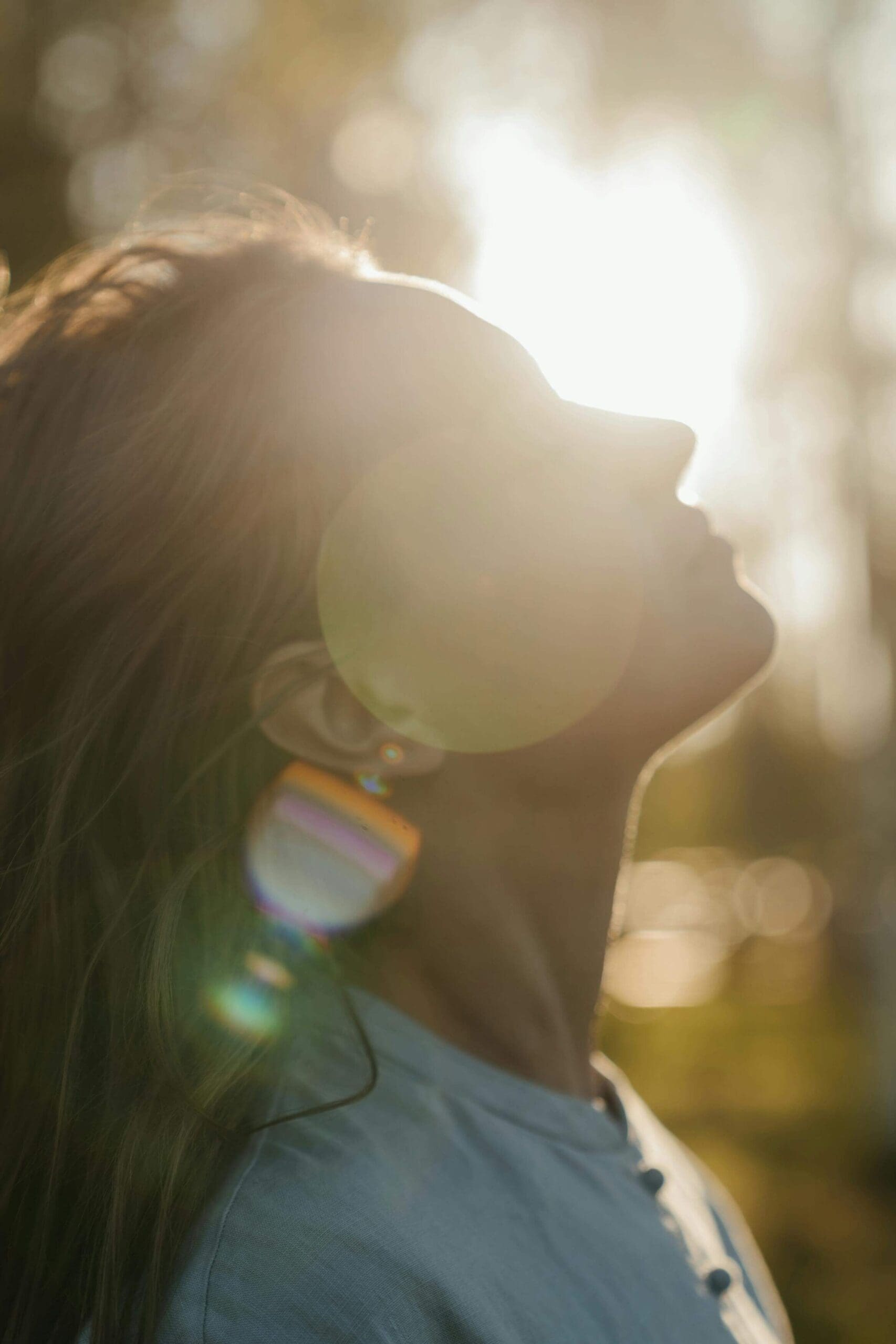 A woman tilts her head back in warm golden sunlight outdoors. Could codependency be a hidden symptom of unprocessed trauma? An online relational trauma therapist in Palm Beach, FL can help you heal.