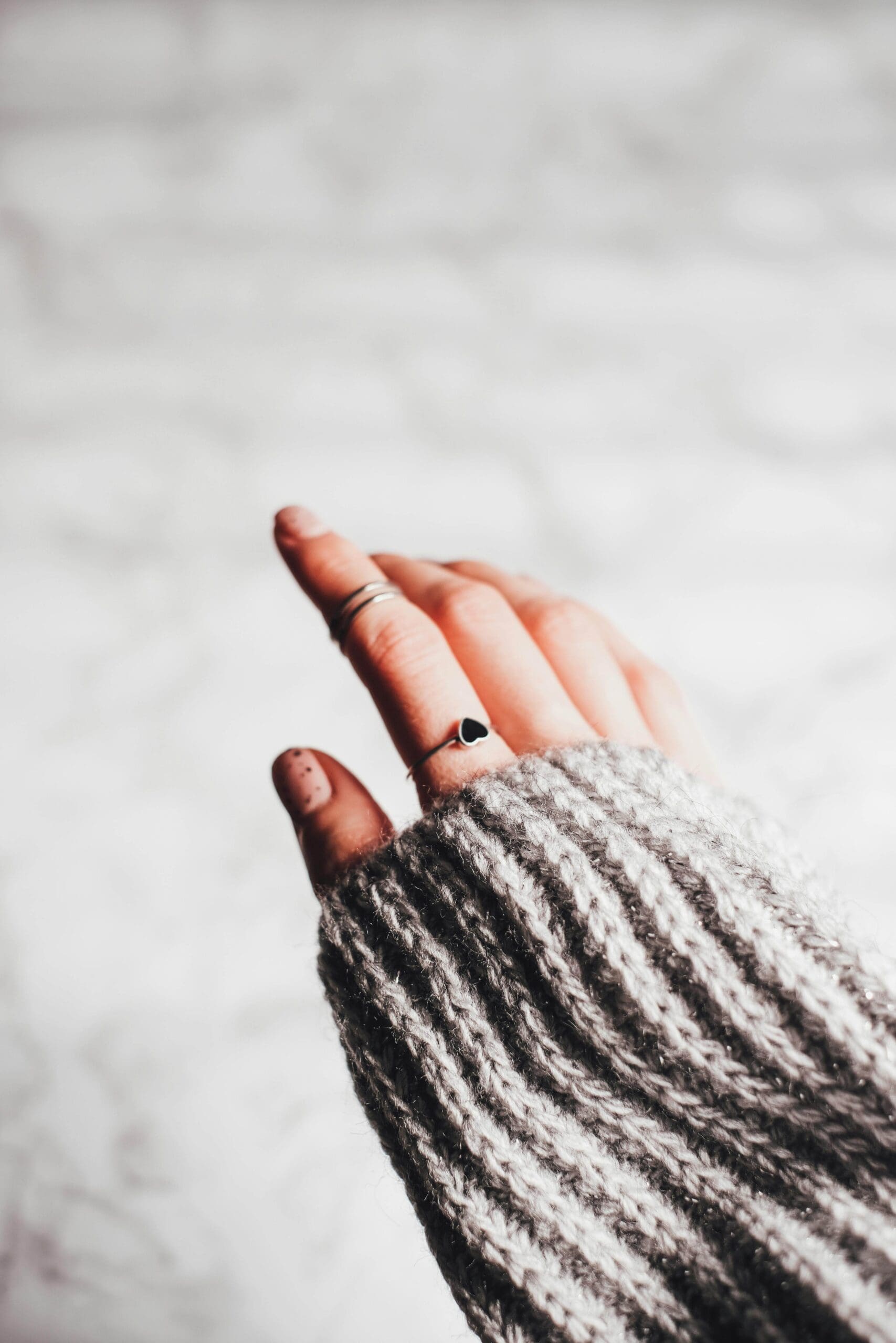 A close-up of a ringed hand emerging from a chunky striped knit sweater. Could codependency be rooted in past trauma you haven't fully processed yet? A relational trauma therapist in Palm Beach, FL, can help you understand why.