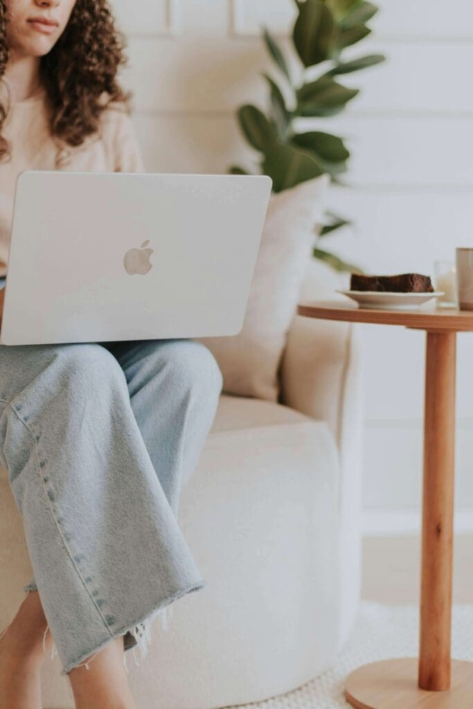 A woman sits on a couch working on a laptop in a calm. Do people-pleasing behaviors develop when someone feels responsible for keeping others comfortable? Relational trauma therapy in Palm Beach, FL, helps uncover patterns rooted in early relationship dynamics.