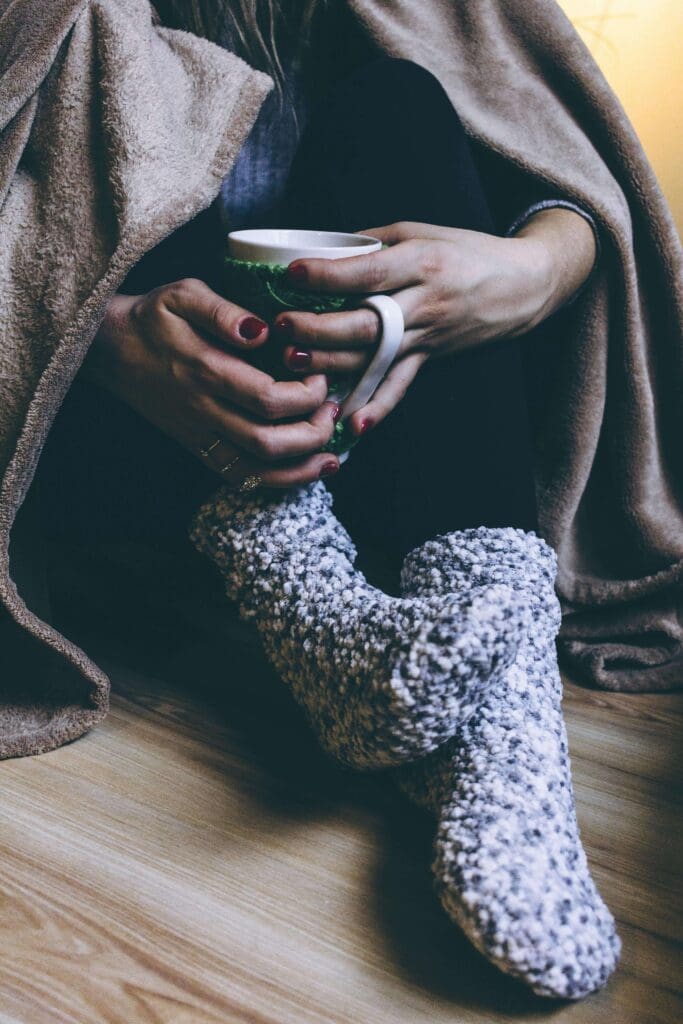 A woman holds a warm mug, feet tucked into cozy fuzzy socks. Does simple self-care like resting with tea still trigger guilt or a sense of not deserving it? Relational trauma therapy in Palm Beach, FL can help you reclaim comfort without the weight of shame.