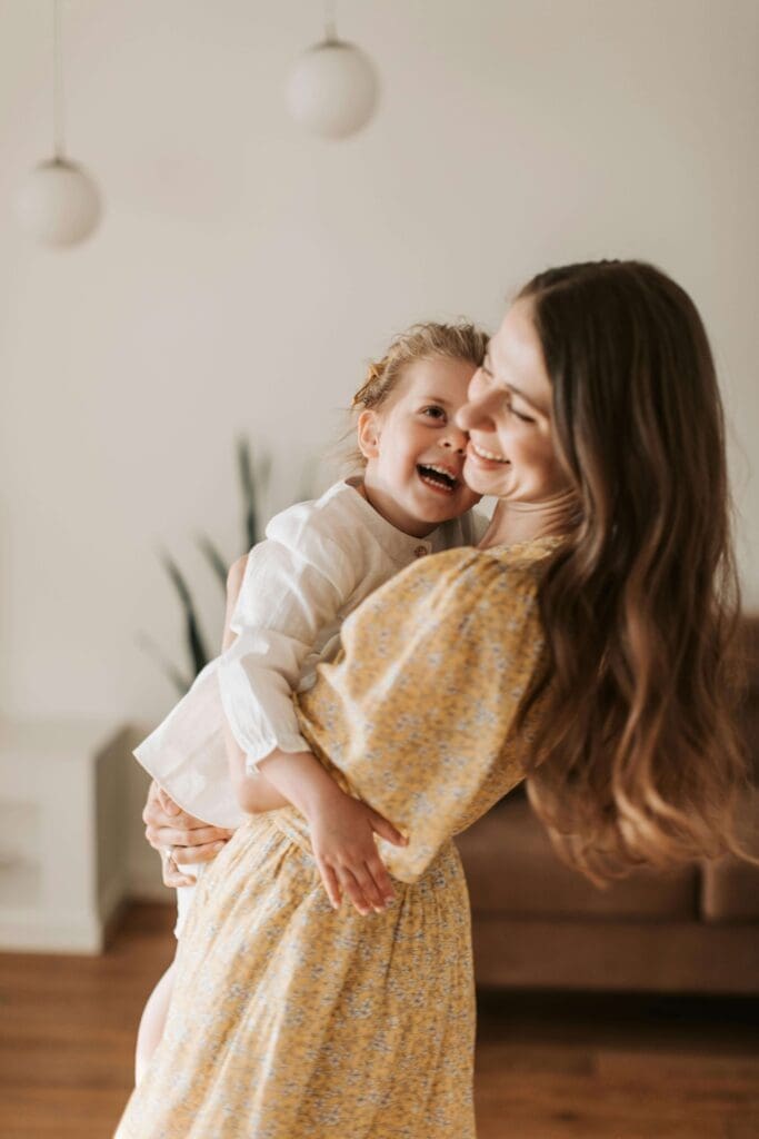 Yellow dress | parenting with unhealed trauma palm beach | online trauma therapist | relational trauma therapy | Palm Beach, Florida | Wellington | Boynton Beach | The Island | The Colony Hotel A mother in a yellow floral dress spins and laughs with her young daughter. Is parenting bringing up emotions you didn't expect? Relational trauma therapy in Palm Beach, FL can help you break old cycles and parent from a place of healing.