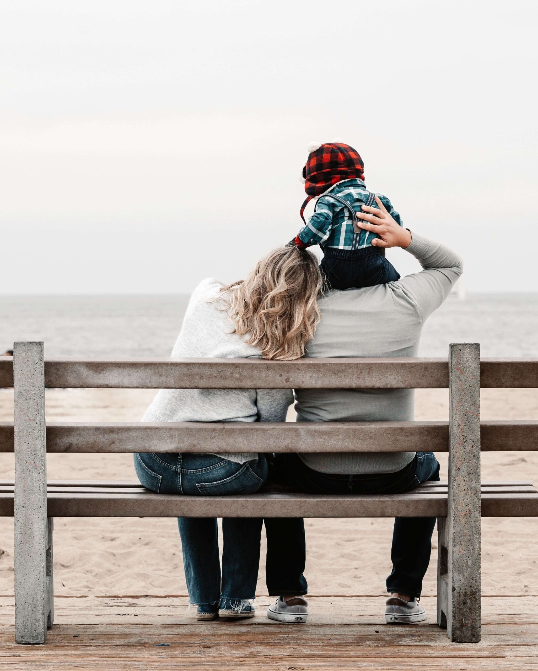 A family sits closely on a boardwalk bench. Are you struggling to prioritize self-care while managing the constant demands of motherhood this summer? A relational trauma therapist in Palm Beach, FL, can support you in finding balance.