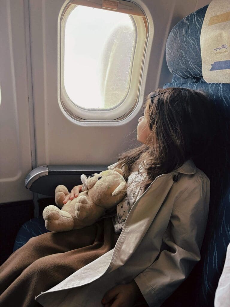 Airplane window | how to enjoy a family vacation palm beach | trauma therapy for high achievers plam beach | complex relational trauma | Palm Beach, Florida | Jupiter | Palm Beach Gardens | Wall Street South | Whitehall A young girl hugs a stuffed teddy bear and gazes out an airplane window. Are you a woman who plans every detail of the family vacation & arrives already exhausted before it begins? A relational trauma therapist in Palm Beach, FL, can help you understand why.