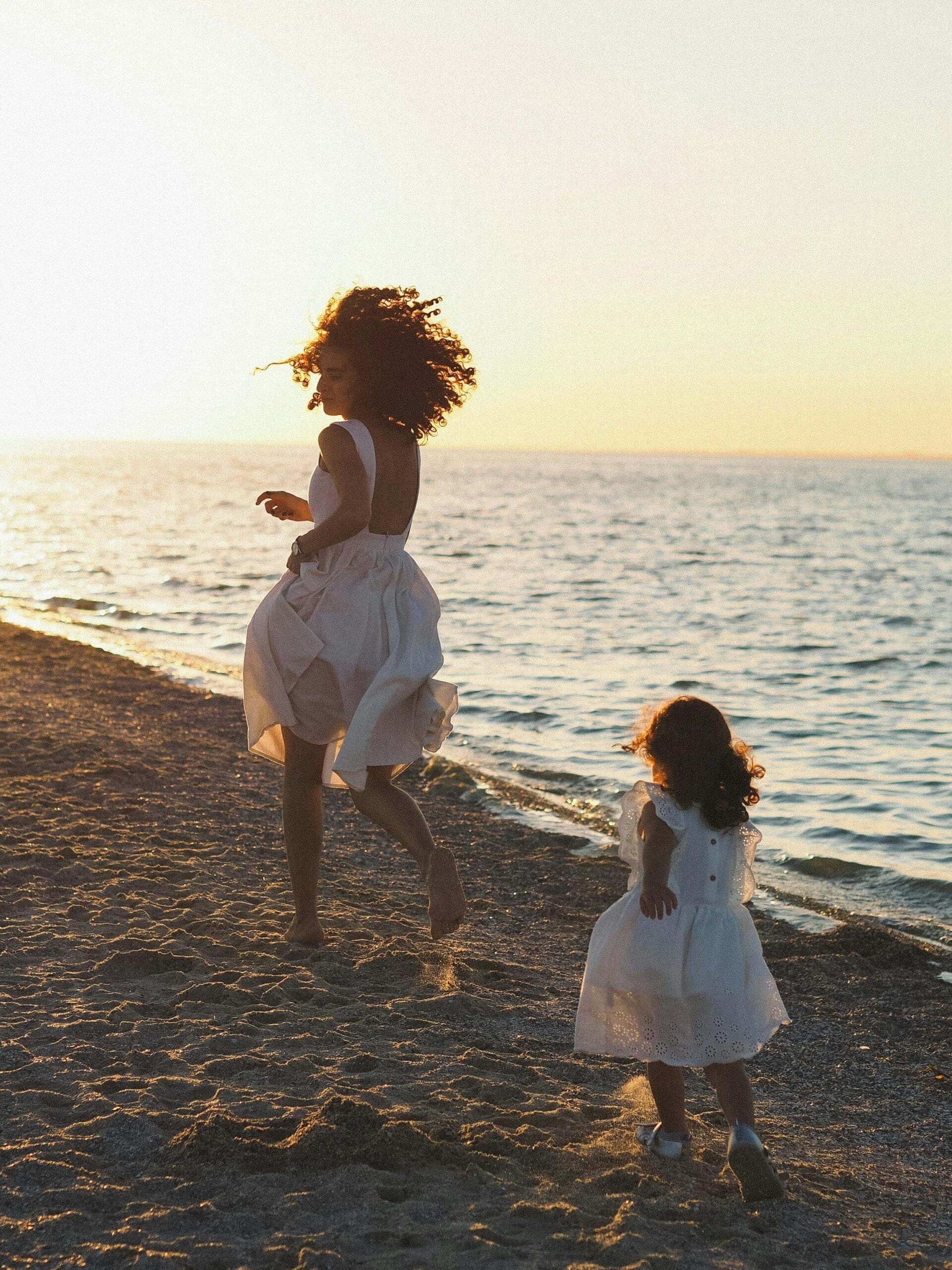 White dresses | mother self care palm beach | relational ptsd | online trauma therapist | Palm Beach, Florida | Boca Raton | Flamingo Park | Northwood Shores | Worth Avenue A mother and daughter in white dresses run along a beach. Are you a mother wondering how to truly enjoy summer while balancing the needs of everyone around you? A relational trauma therapist in Palm Beach, FL, can help you reclaim joy for yourself.