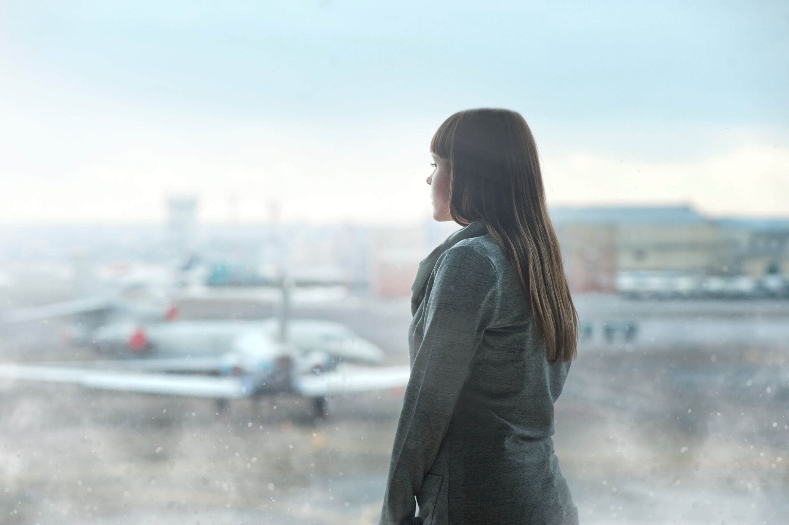 A woman in a gray sweater stands alone at an airport window. Do you spend every family vacation managing everyone else while never being present? Relational trauma therapy in Palm Beach, FL, can help you finally reclaim your own experience.