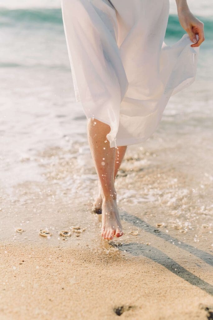 Shoreline walk | summer pressure on women palm beach | trauma therapy for high achievers plam beach | complex relational trauma | Palm Beach, Florida | Jupiter | Palm Beach Gardens | Wall Street South | Whitehall A woman in a flowing white dress walks barefoot along a sunlit shoreline. Are you finding that summer has arrived but the happiness you expected still feels just out of reach? A relational trauma therapist in Palm Beach, FL, can help you understand why.