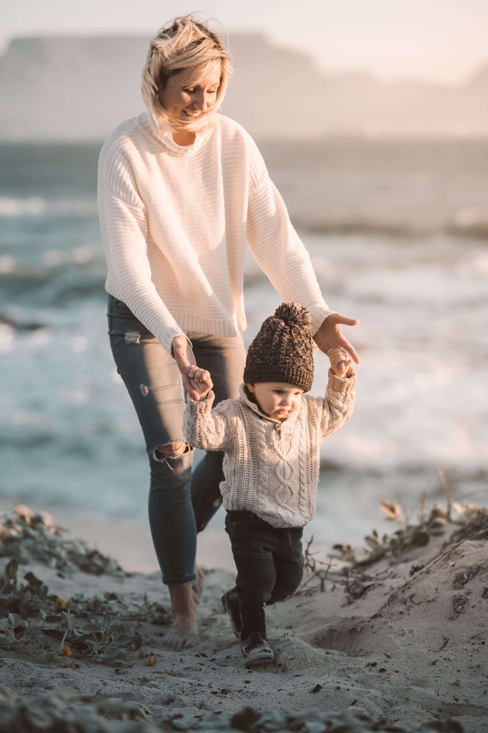 Smiling mother | summer pressure on women palm beach | online trauma therapist | relational trauma therapy | Palm Beach, Florida | Wellington | Boynton Beach | The Island | The Colony Hotel A smiling mother guides her toddler as they walk along a beach. Are you a mother who gives endlessly to others but struggles to carve out time for your own self-care? Relational trauma therapy in Palm Beach, FL, can help you rediscover yourself.