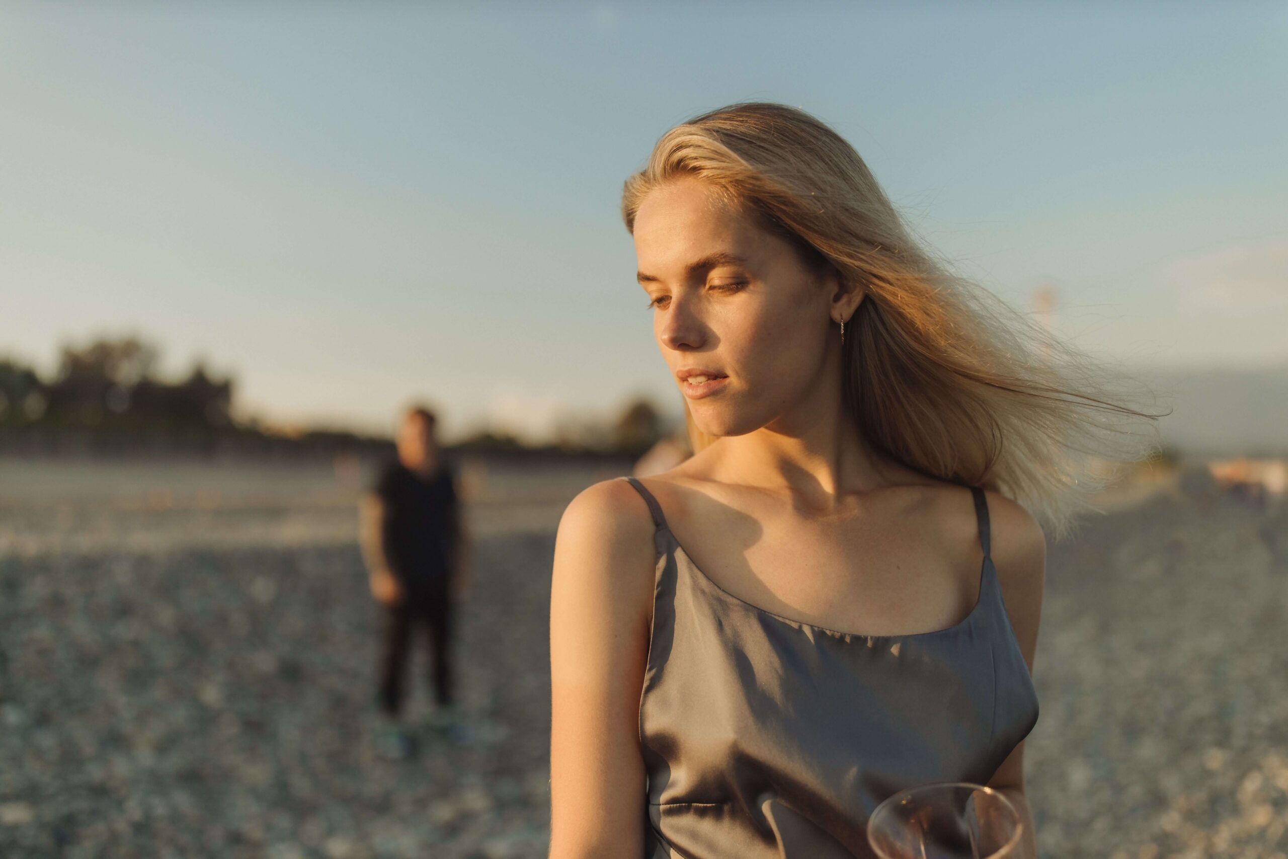 A woman looks down thoughtfully while a man stands at a distance behind her. Why does one partner often end up carrying the emotional labor alone? A relational trauma therapist in Palm Beach, FL can help couples close that gap.