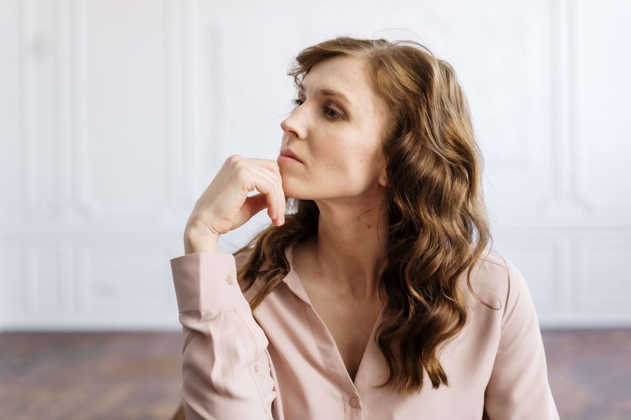 A woman rests her chin on her hand, gazing off thoughtfully with a worried expression. Do you find yourself bracing for the other shoe to drop in your relationships? An online relational trauma therapist in Palm Beach, FL can help you work through these fears.