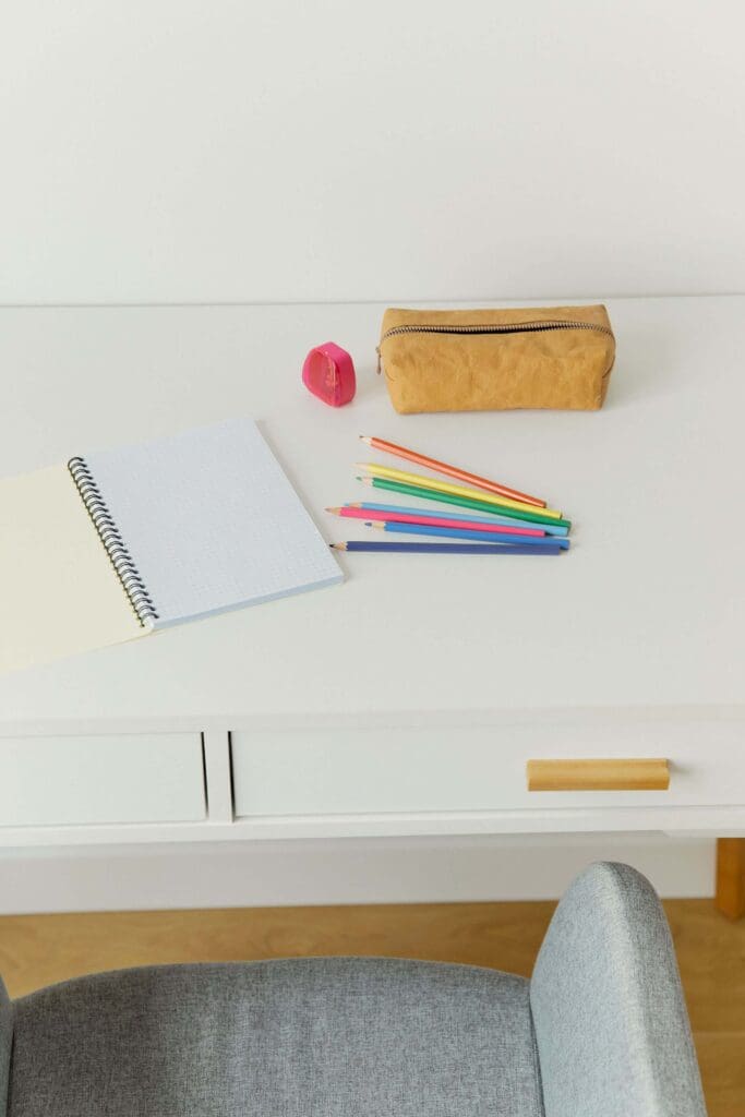 A tidy desk is set with a notebook, colored pencils, and a pencil case for the new school year. Does back-to-school season already have you feeling overwhelmed? Online relational trauma therapy in Palm Beach, FL supports moms through this transition.