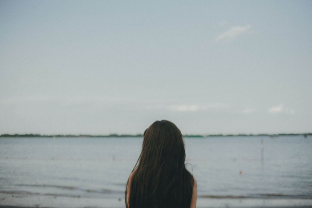 A woman with long dark hair stands alone at the water's edge. Do relationships sometimes feel like a confusing push and pull you can't quite explain? An online relational trauma therapist in Palm Beach, FL can help you find clarity and stability.