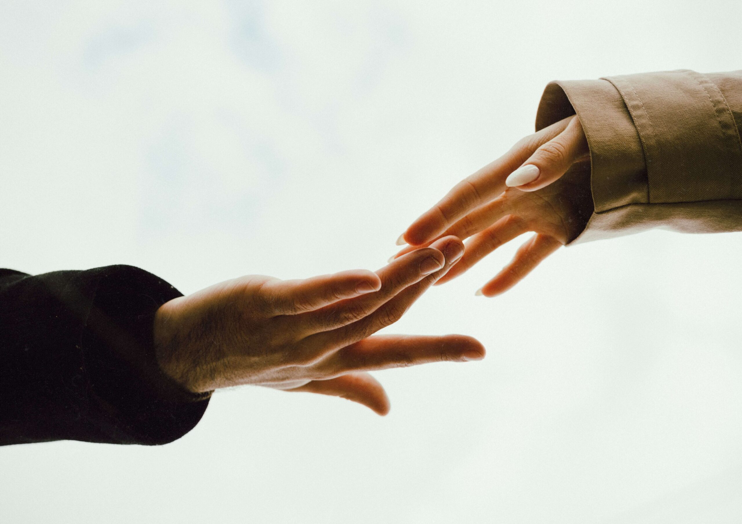 Two hands reach toward each other against a plain white sky. Is disorganized attachment making it hard to trust closeness in your relationships? Online relational trauma therapy in Palm Beach, FL offers support for breaking this exhausting cycle.