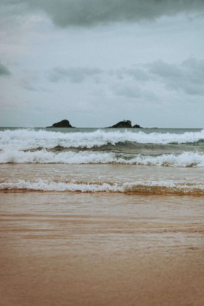 Beach waves | emotionally disconnected palm beach, fl | relational trauma therapy | online trauma therapist | Palm Beach, Florida | Boca Raton | Flamingo Park | Northwood Shores | Worth Avenue Waves roll onto a quiet, sandy beach beneath a heavy, overcast sky. Could what looks like calm actually be a sign of emotional suppression? Online relational trauma therapy in Palm Beach, FL can help you tell the difference between peace and disconnection.