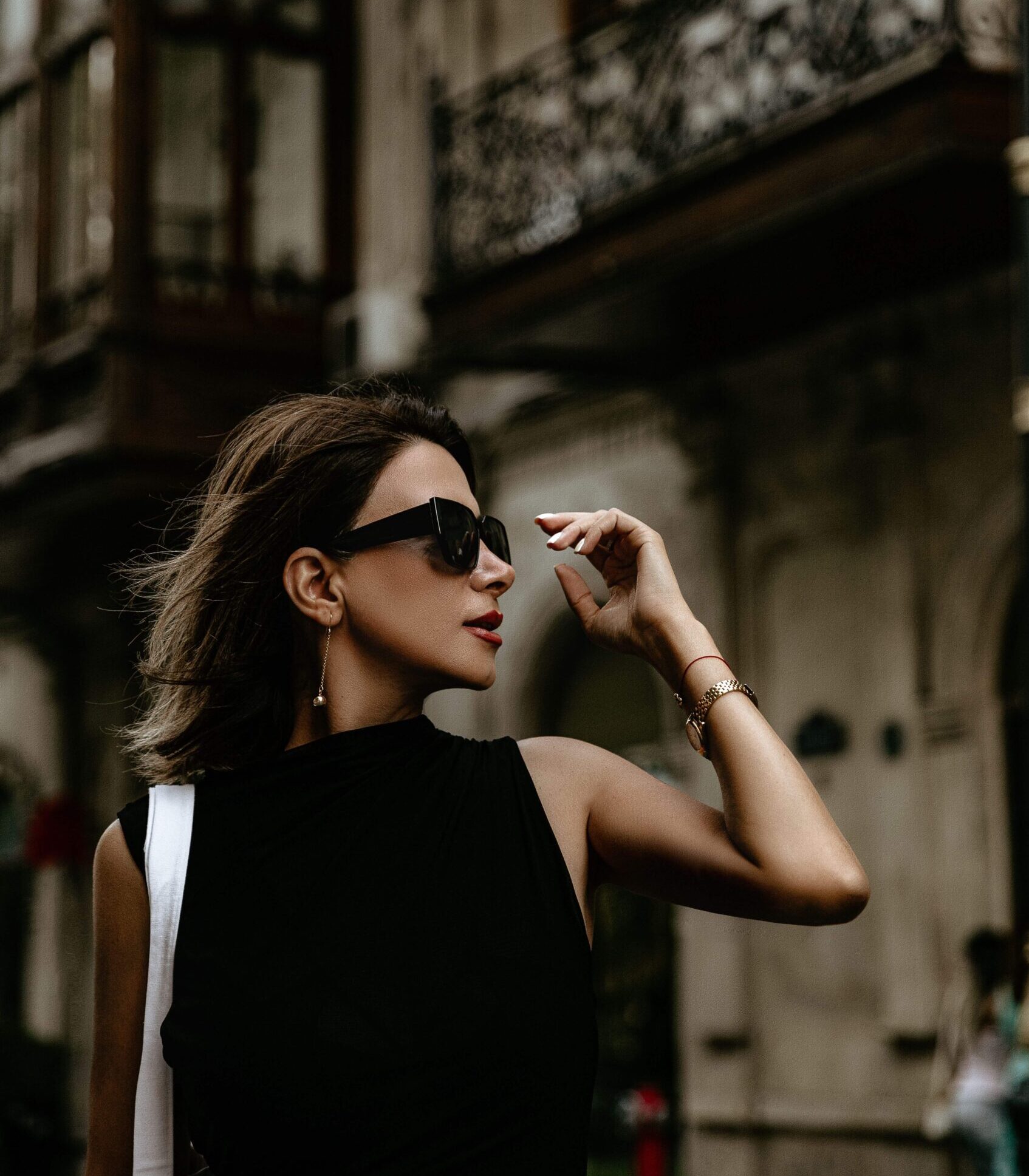 A woman in sunglasses and a sleek black outfit poses elegantly near an ornate historic building. Could imposter syndrome linger beneath even the most polished exterior? Online relational trauma therapy in Palm Beach, FL helps uncover the roots of these persistent doubts.