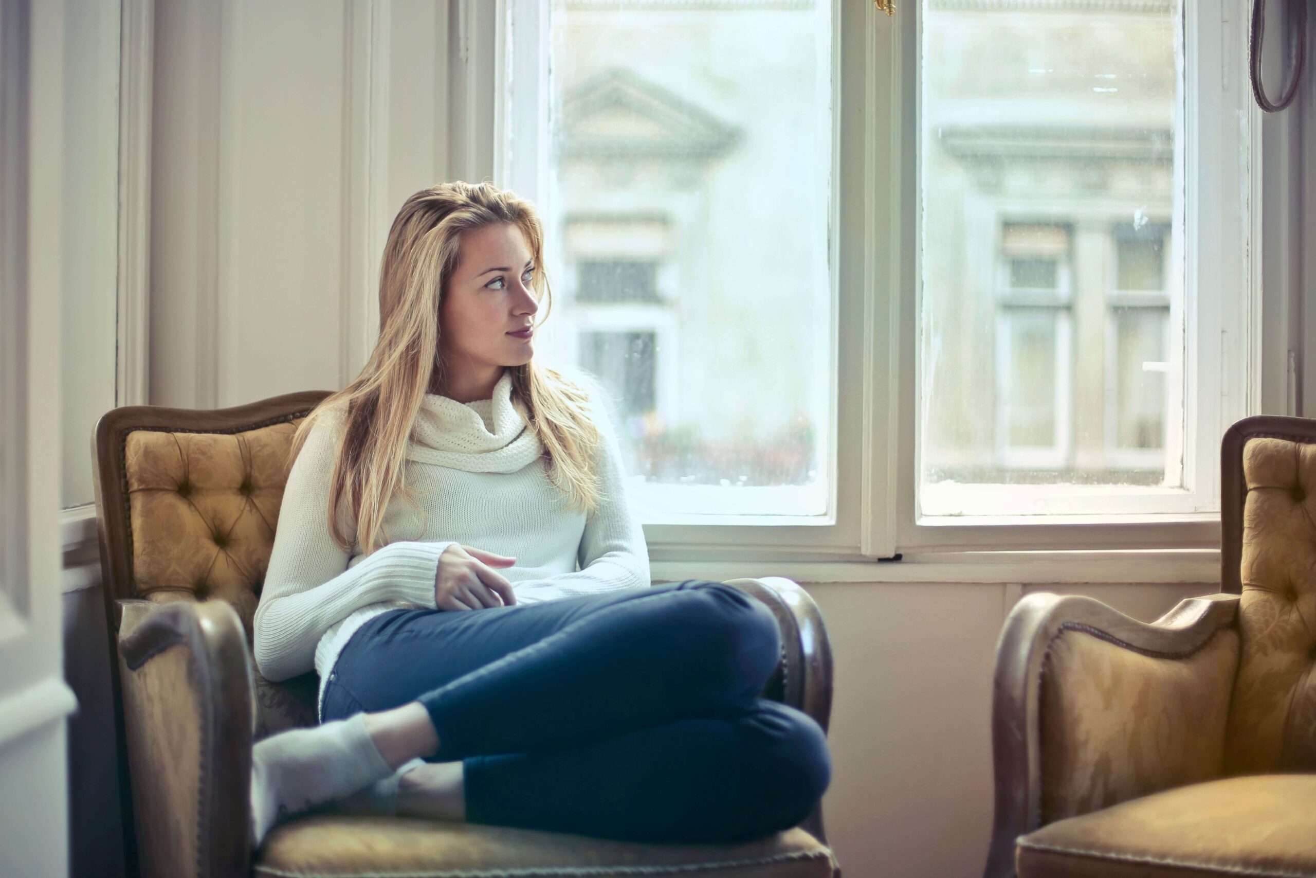 A woman sits in an armchair by a window, gazing outside with a thoughtful, distant expression. Does asking for help ever feel more dangerous than simply doing everything yourself? An online relational trauma therapist in Palm Beach, FL can help you understand and shift this pattern.